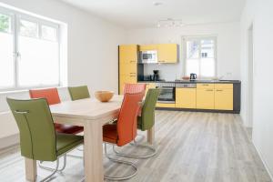 eine Küche und ein Esszimmer mit einem Holztisch und Stühlen in der Unterkunft Apartmenthaus Eldena in Greifswald