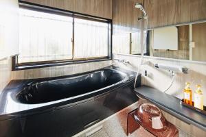 a black bath tub in a bathroom with a window at マイグレフラット in Ito +25 photos