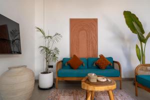 a living room with a blue couch and a table at Enaya Villa by Betterplace in Tumbak Bayuh