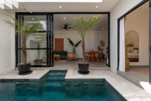 a pool in a house with palm trees in it at Enaya Villa by Betterplace in Tumbak Bayuh