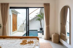a bedroom with a bed and sliding glass doors at Enaya Villa by Betterplace in Tumbak Bayuh