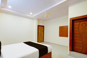 a bedroom with a bed and a wooden door at Hotel O Balaji R Square in Surūrnagar