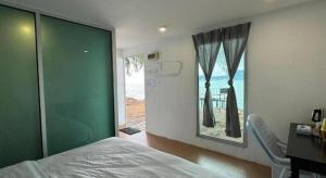 a bedroom with a bed and a desk and a window at Rockbund Fishing Chalet in Kampong Batu Gajah
