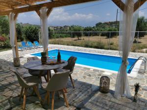 a patio with a table and chairs next to a swimming pool at Kefalonia Olive House private pool in Xi