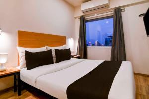 a hotel room with a large bed with a window at Townhouse Oak VIP Road NSCB Airport in kolkata