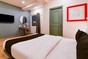 a bedroom with a large white bed and a television at Townhouse Oak VIP Road NSCB Airport in kolkata