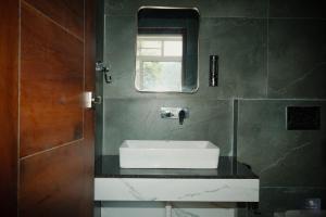 a bathroom with a white sink and a mirror at Chester Oak Kasauli - Premium rooms and Exclusive Villa in Kasauli +11 photos