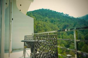a balcony with a table and a view of a mountain at Chester Oak Kasauli - Premium rooms and Exclusive Villa in Kasauli