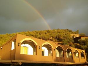 a rainbow in the sky above a building at La Loma Resort in Merlo