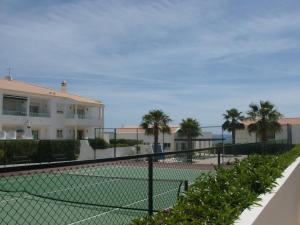 a tennis court in front of a building with palm trees at Apartamento Sunny Velamar in Patroves