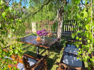 a wooden table with chairs and a vase of purple flowers at Penzion U Skokovské báby in Žehrov