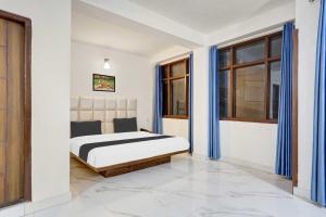 a bedroom with a bed with blue curtains at Townhouse Oak Kachighati ISBT Shimla in Shimla
