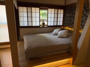 - une chambre avec un lit avec deux oreillers et une fenêtre dans l'établissement 京都 三日月 Mikazuki, à Kyoto