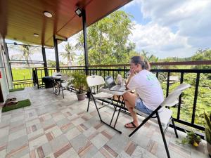 a woman sitting at a table on a patio at RAK Apartment in Malvar