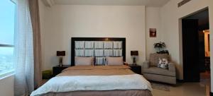 a bedroom with a large bed and a chair at JLT 1BR Marina Skyline View in Dubai +15 photos