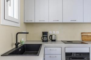 a kitchen with white cabinets and a sink at Iremia Coastal Retreat - Private Sea View Terrace in Neo Klima