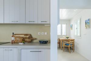 a kitchen with white cabinets and a table with a chair at Iremia Coastal Retreat - Private Sea View Terrace in Neo Klima +39 photos