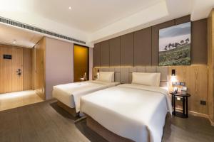 a hotel room with two beds and a painting on the wall at Atour Hotel Zhengzhou East Railway Station Provincial Government in Zhengzhou