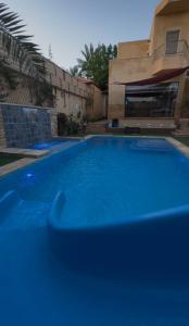 a blue swimming pool in front of a house at Orient Villa-Dead Sea in Sowayma