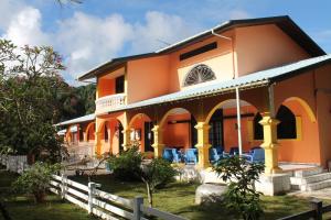 une maison orange avec des chaises devant elle dans l'établissement Hotel L'ebene Verte, à Matoury