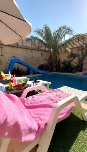 a table with a pink blanket next to a pool at Orient Villa-Dead Sea in Sowayma