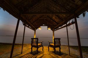 two chairs sitting under a gazebo on the beach at Alaya Stays Vembanad House Heritage Lakeside Villa with Garden in Alleppey +68 photos