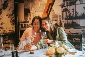 two women sitting at a table with wine glasses at Svinøya Rorbuer in Svolvær