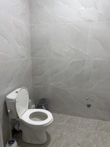 a bathroom with a toilet and a tiled wall at Yunusabad Comfort House in Yunusobod