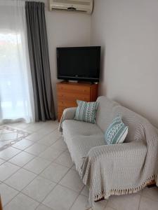 un salon avec un canapé et une télévision à écran plat dans l'établissement Anna Family Apartment, à Nikiti