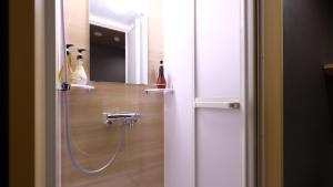 a shower with a hose in a bathroom with a mirror at Onyado Nono Matsumoto Natural Hot Spring in Matsumoto