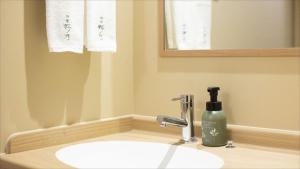 a bathroom sink with a bottle of soap on it at Onyado Nono Matsumoto Natural Hot Spring in Matsumoto