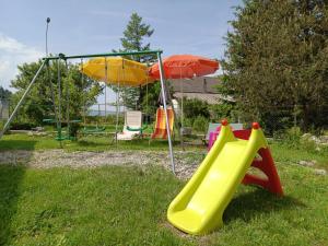 a playground with a slide and an umbrella at Le Havre des Tourbières in Brot-Plamboz
