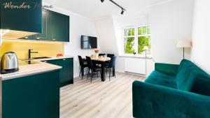 kuchnia i salon z zielonymi szafkami i kanapą w obiekcie Wonder Home - Apartament blisko Ski Arena, szlaków turystycznych i Kościółka Wang w mieście Karpacz