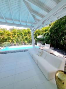 a white patio with white couches and a pool at Sandy Bay Villa Opale in Le Moule