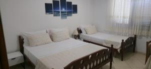 two beds in a room with white walls and windows at Vila Cikaj in Durrës
