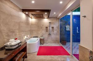 bagno con vasca, doccia e tappeto rosso di Mayfair Lagoon a Bhubaneshwar