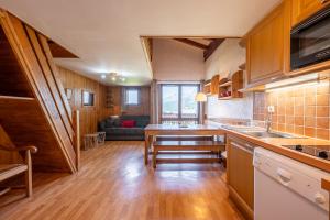a kitchen with wooden cabinets and a living room at Appartement 12 - Les Aravis in Crest-Voland