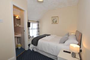 a bedroom with a white bed and a bathroom at California Inn in Brynteg