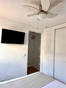 ein Schlafzimmer mit einem Deckenventilator und einem TV an der Wand in der Unterkunft First line with ocean views in Cala en Forcat