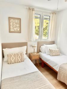 zwei Betten in einem Zimmer mit zwei Fenstern in der Unterkunft First line with ocean views in Cala en Forcat
