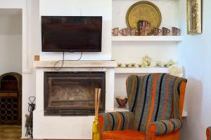 a living room with a fireplace with a tv and a chair at Alojamiento Rural Casilla Miguelin in Montilla