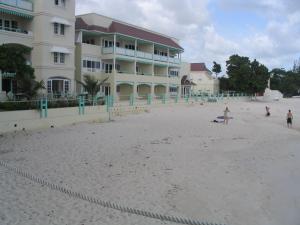 a beach with people and a surfboard on it at Coral Mist Beach Hotel in Bridgetown