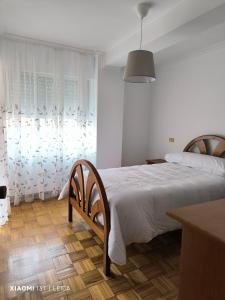 a white bedroom with a bed and a table at Can do Penedo 8 in Bueu