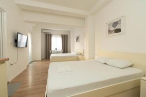 a white room with two beds and a television at Lumi Apartments in Gevgelija