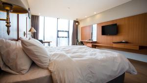 - un grand lit blanc dans une chambre d'hôtel dans l'établissement J Square Hotel and Wedding, à Jinju