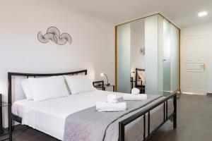 a bedroom with a large white bed and a mirror at Fexulis Studios & Suites in Agios Nikolaos