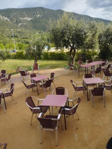 Un grupo de mesas y sillas con montañas al fondo. en Fonda Aparicio, en Fuentespalda