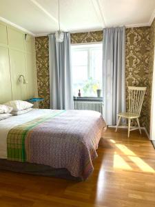 a bedroom with a bed and a chair and a window at Village house & garden for summer hangout near Sankt Olof in Onslunda
