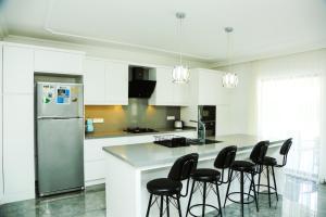 a kitchen with white cabinets and black bar stools at Villa Kaan in Ortaca