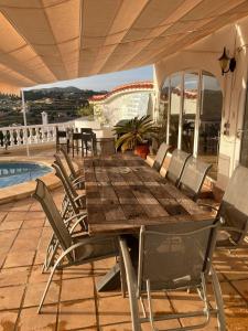 コンブレ・デル・ソルにあるLarge villa, great view with private swimming poolのパティオにある木製のテーブルと椅子